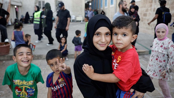 A woman talks with a child in a school turned into a temporary shelter for displaced people, during a visit by Hezbollah members of parliament, amid the ongoing hostilities between Hezbollah and Israel, in Beirut, Lebanon, October 9, 2024. REUTERS/Louisa Gouliamaki
