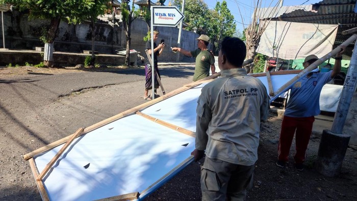 Satpol PP Buleleng menurunkan baliho milik kontestan Pilkada lantaran dipasang di luar zona yang telah ditentukan, Kamis (10/10/2024). (Foto: Istimewa)