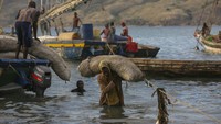 Pekerja menurunkan karung arang dari perahu untuk dijual di pasar.