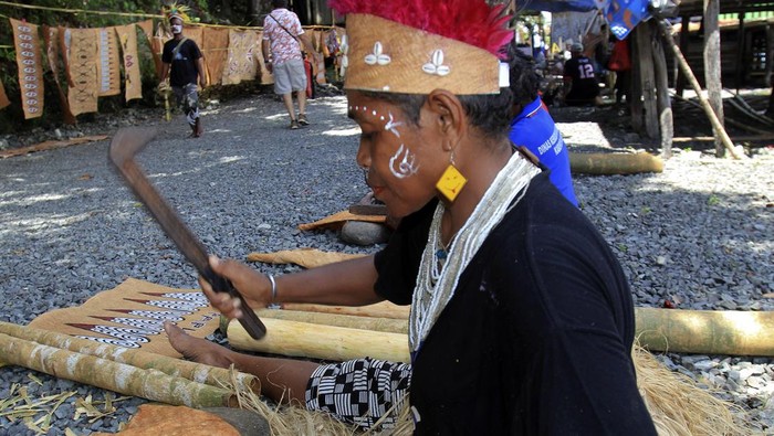 Kerajinan Kulit Kayu Papua Pikat Turis Asing Warga menjelaskan lukisan dari kulit kayu kepada wisatawan mancanegara pada Festival Kulit Kayu Khombouw di Kampung Asei Besar, Distrik Sentani Timur, Kabupaten Jayapura, Papua, Kamis (10/10/2024). Festival yang pertamakali digelar tersebut bertujuan untuk mengeksplore potensi kerajinan suvenir dan lukisan dari kulit kayu. ANTARA FOTO/Gusti Tanati/YU
