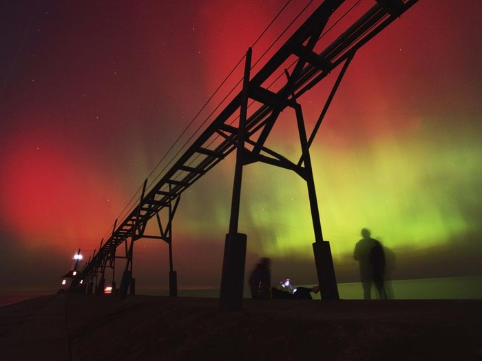 People watch as an aurora borealis, also known as the northern lights, lights up the night sky from Montrose Point, Thursday, Oct. 10, 2024, in Chicago. (Tyler Pasciak LaRiviere/Chicago Sun-Times via AP)