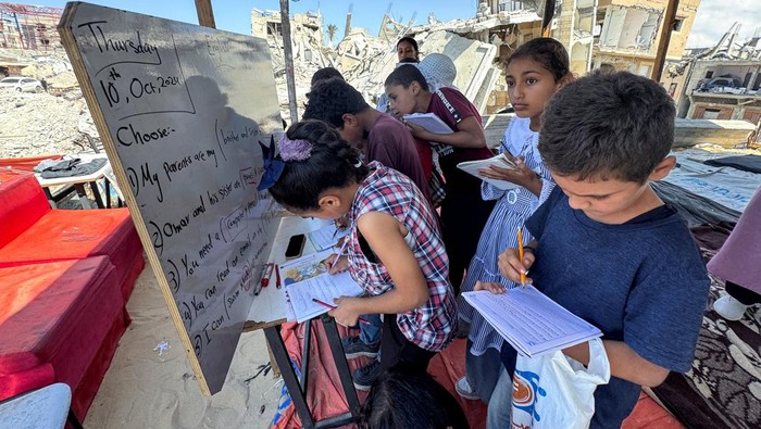 Palestinian students attend a class in a tent set up on the ruins of the house of teacher Israa Abu Mustafa, as war disrupts a new school year, amid the Israel-Hamas conflict, in Khan Younis, in the southern Gaza Strip, October 10, 2024. REUTERS/Mohammed Salem
