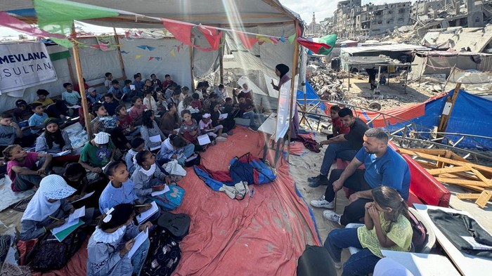 Semangat Belajar Anak-anak Palestina di Tengah Bombardir Israel Palestinian students attend a class in a tent set up on the ruins of the house of teacher Israa Abu Mustafa, as war disrupts a new school year, amid the Israel-Hamas conflict, in Khan Younis, in the southern Gaza Strip, October 10, 2024. REUTERS/Mohammed Salem