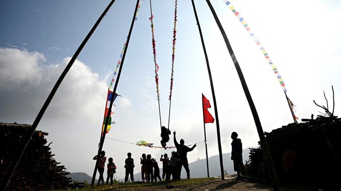 Anak-anak hingga remaja bermain ayunan yang terbuat dari bambu di Kathmandu, Nepal. Kegiatan itu merupakan salah satu dari perayaan festival Dashain.
