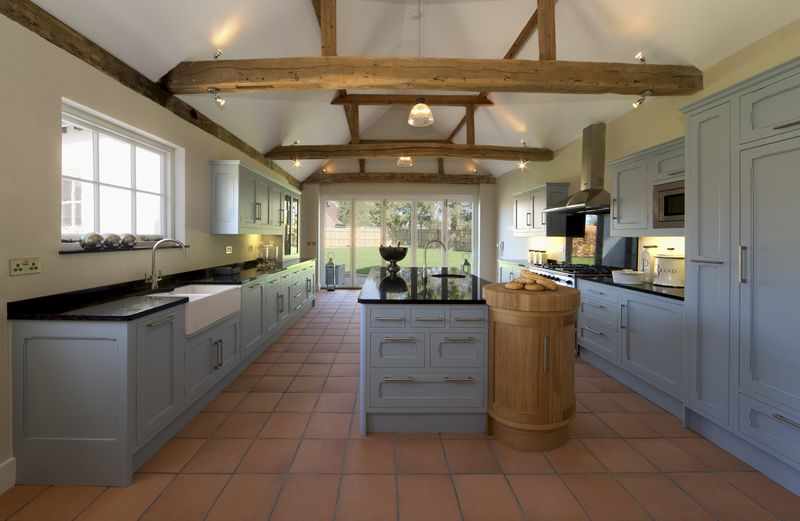 a beautiful farmhouse kitchen in a fully restored and rebuilt farm. Old, weathered oak beams support the roof and ceiling. Brand new terracotta flooring compliments the pastel toned powder blue cupboards and large kitchen island. This is a modern featured kitchen with all the appliances but constructed in a traditional style and being faithful to the 500 year old building.