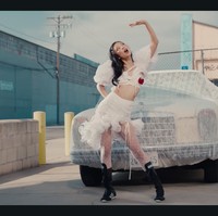 Tampil dengan gaya coquette. Jennie BLACKPINK mengenakan kostum putih rancangan Kitschy Couture. Dengan detail atasan crop top berlengan balon dan tambahan stoking. Dia memberikan sentuhan sporty dengan koleksi sepatu Adidas Japan VH Shoes seharga Rp 2,1 juta. Foto: dok. YouTube JENNIE