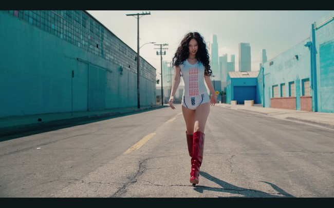 Seperti yang terlihat dalam foto teaser Mantra, Jennie BLACKPINK memadukan kaos putih Raga Melak seharga Rp 1,3 jutaan dengan celana renang Rp 1,7 jutaan. Ankle boots merah jadi statement penampilannya. Foto: dok. YouTube JENNIE