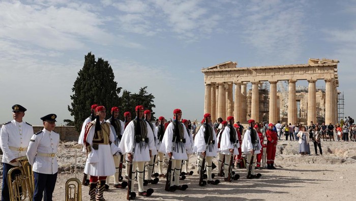 People watch as Greek Presidential Guards, known as Evzones, form a guard of honour during a ceremony for the 80th anniversary of the liberation of Athens from Nazi occupation, next to the Parthenon temple, atop the Acropolis hill in Athens, Greece, October 12, 2024. REUTERS/Louiza Vradi