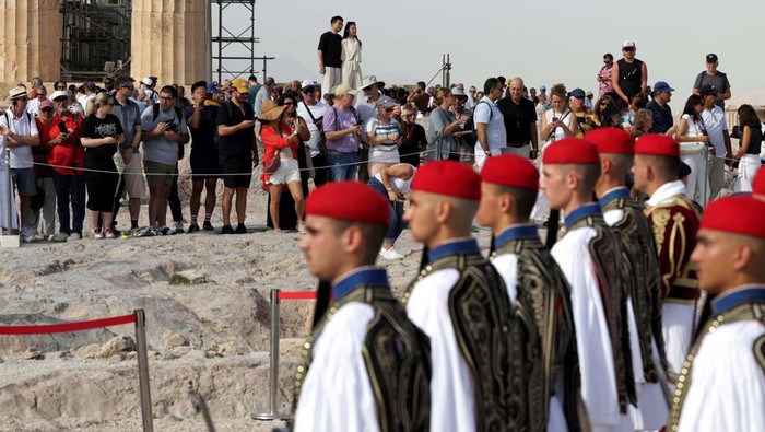 Peringatan 80 Tahun Pembebasan Athena dari Nazi People watch as Greek Presidential Guards, known as Evzones, form a guard of honour during a ceremony for the 80th anniversary of the liberation of Athens from Nazi occupation, next to the Parthenon temple, atop the Acropolis hill in Athens, Greece, October 12, 2024. REUTERS/Louiza Vradi