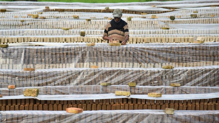 Perajin menutup batu bata yang dijemur menggunakan terpal di Pakam, Deli Serdang, Sumatera Utara, Sabtu (12/10/2024). Tingginya curah hujan di daerah tersebut berdampak pada merosotnya produksi batu bata, jika musim kemarau perajin mampu memproduksi hingga 15.000 batu bata sedangkan pada musim penghujan hanya 5.000 ribu bata, dengan harga jual Rp300 per batu bata. ANTARA FOTO/Fransisco Carolio/Spt.