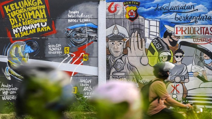 Pengendara sepeda motor melintas di depan mural keselamtan berkendara dan tertib berlalu lintas di Kota Serang, Banten, Sabtu (12/10/2024). Mural tersebut dibuat guna memberikan edukasi kepada pengguna kendaraan agar mentaati peraturan lalu lintas untuk menciptakan keselamatan dalam berkandara. ANTARA FOTO/Muhammad Bagus Khoirunas/Spt.