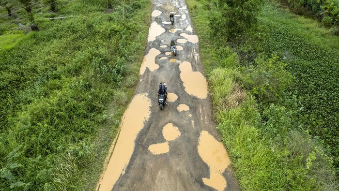 Foto udara pengendara melintasi jalan rusak dan berlubang di Berbak, Tanjung Jabung Timur, Jambi, Minggu (13/10/2024). Warga setempat menyebutkan, jalan milik provinsi yang berada di perbatasan Kabupaten Tanjung Jabung Timur dengan Muaro Jambi dan menjadi jalur utama masyarakat Berbak menuju Kota Jambi itu tidak pernah mendapatkan pengaspalan dan kondisi yang buruk itu membahayakan pengguna jalan. ANTARA FOTO/Wahdi Septiawan/aww.