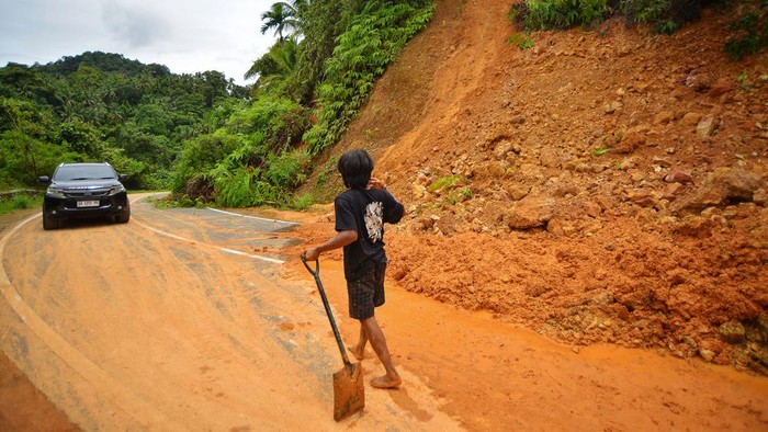 Jalan lingkar Nipah-Teluk Bayur Longsor Warga memandu pengendara melewati jalan yang longsor di Jalan Lingkar Nipah-Teluk Bayur Padang, Sumatera Barat, Minggu (13/10/2024). Akibat intensitas hujan tinggi tiga hari terakhir, membuat dua titik longsor di ruas jalan alternatif tersebut yang membuat jalan tidak bisa dilewati mobil untuk sementara, kecuali motor. ANTARA FOTO/Iggoy el Fitra/foc.