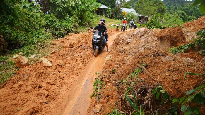 Jalan lingkar Nipah-Teluk Bayur Longsor Warga memandu pengendara melewati jalan yang longsor di Jalan Lingkar Nipah-Teluk Bayur Padang, Sumatera Barat, Minggu (13/10/2024). Akibat intensitas hujan tinggi tiga hari terakhir, membuat dua titik longsor di ruas jalan alternatif tersebut yang membuat jalan tidak bisa dilewati mobil untuk sementara, kecuali motor. ANTARA FOTO/Iggoy el Fitra/foc.