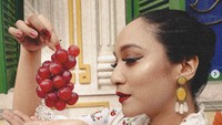 Bella Fawzi berpose dengan anggur merah yang terlihat segar. Ia melakukan pemotretan ini dalam rangka peluncuran lagunya yang berjudul Anggur Asmada pada Februari 2024. Foto: Instagram bellafawzi_