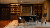 Ini ruangan kantor Presiden AFC yang tampak hangat dengan banyak elemen kayu, karpet, dan pencahayaan kuning. 