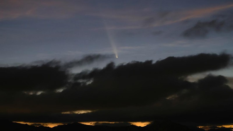 A satellite leaves a trail of light across the tail of the comet C/2023 A3 (Tsuchinshan-ATLAS), with an 80,000 year orbit, known as the comet of the century, after sunset in Ronda, Spain, October 13, 2024. REUTERS/Jon Nazca