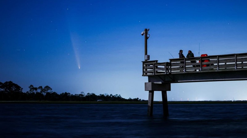Comet C/2023 A3 (Tsuchinshan-ATLAS) is visible shortly after sunset in the western sky over the Fisherman’s Walk Pier as two men fish, in Tybee Island, Georgia, U.S. October 13, 2024.  REUTERS/Sam Wolfe     TPX IMAGES OF THE DAY