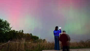 Orang-orang menyaksikan aurora borealis menerangi langit malam dari Montrose Point, Kamis, 10 Oktober 2024, di Chicago, AS. Foto: Tyler Pasciak LaRiviere/Chicago Sun-Times via Komonews