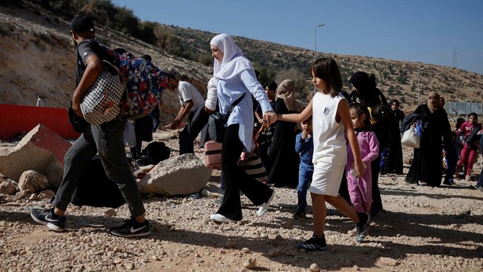 People wait for further transportation, after crossing Lebanon into Syria on foot at the Masnaa border crossing, after Israeli strikes earlier this month that Lebanons transport minister said had closed off the road to vehicles. October 14, 2024. REUTERS/Louisa Gouliamaki