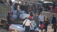 Orang-orang menunggu transportasi lebih lanjut, setelah menyeberangi Lebanon ke Suriah dengan berjalan kaki di perbatasan Masnaa, setelah serangan Israel awal bulan ini yang menurut menteri transportasi Lebanon telah menutup jalan bagi kendaraan dalam foto yang diambil pada Senin (14/10/2024).