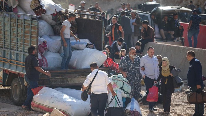 People wait for further transportation, after crossing Lebanon into Syria on foot at the Masnaa border crossing, after Israeli strikes earlier this month that Lebanon's transport minister said had closed off the road to vehicles. October 14, 2024. REUTERS/Louisa Gouliamaki