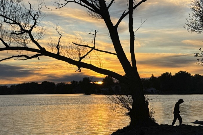 As the sun sets, a man walks by the lake Wilcox at the Oak Ridges neighborhood, about 40 km, 24.8 mile north of Toronto, Monday, Oct. 14, 2024. (AP Photo/Kamran Jebreili)