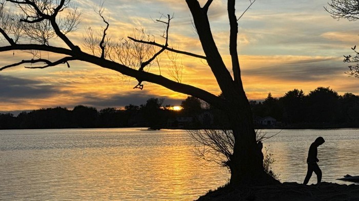 As the sun sets, a man walks by the lake Wilcox at the Oak Ridges neighborhood, about 40 km, 24.8 mile north of Toronto, Monday, Oct. 14, 2024. (AP Photo/Kamran Jebreili)