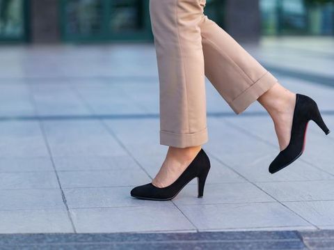 Woman wearing classic black high heel toe shoes. Model posing on the street. Elegant outfit. Close up.