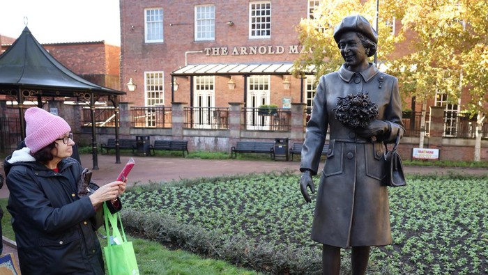 Patung Baru Ratu Elizabeth II Diresmikan di Newcastle People take photographs of a new statue of late Britain's Queen Elizabeth by artist Andy Edwards in Newcastle-under-Lyme, Britain, October 11, 2024. REUTERS/Phil Noble