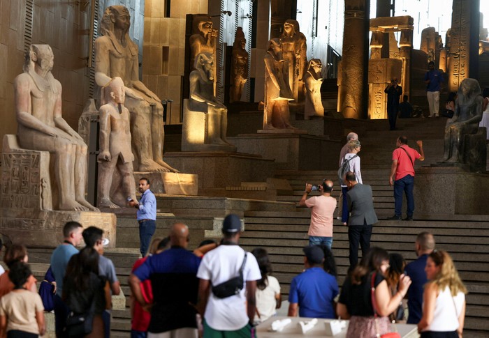 A visitor takes a photo of Pharaonic statues displayed at the Grand Staircase of the Grand Egyptian Museum during a partial trial in Giza, Egypt, October 15, 2024. REUTERS/Mohamed Abd El Ghany      TPX IMAGES OF THE DAY