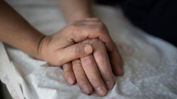 Woman holding the hand of her hospitalized husband