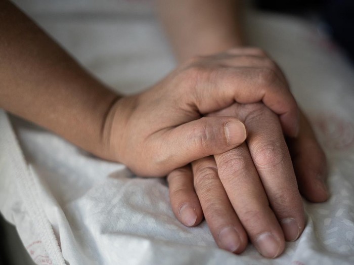 ilustrasi pasien dirawat Woman holding the hand of her hospitalized husband