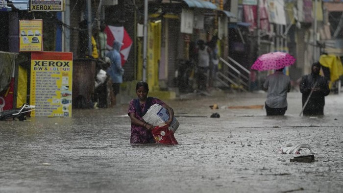 A women wades through a flooded street during heavy rain in Chennai, India, Tuesday, Oct.15, 2024. (AP Photo/Mahesh Kumar A.)