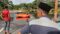 Sejumlah warga menunggu perahu fiberglass untuk bisa melintas karena jalan dan jembatan putus akibat terbawa arus banjir di Desa Alue Siron, Kecamatan Tadu Raya, Nagan Raya, Aceh, Rabu (16/10/2024).   