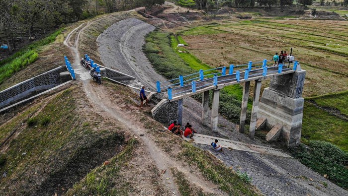 Foto udara sejumlah warga duduk di tepi Waduk Perning yang mengering di Nganjuk, Jawa Timur, Rabu (16/10/2024). Sejak lima bulan terakhir, waduk yang berfungsi untuk perikanan, wisata, dan irigasi seluas sekitar 200 hektar lahan pertanian itu mengering akibat musim kemarau. ANTARA FOTO/Muhammad Mada/foc.