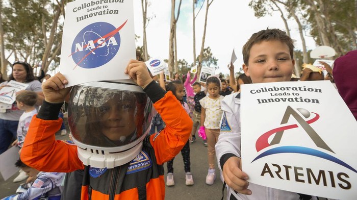 Santiago parent volunteer Stacie Aguesse, right, helps students plant a small Giant Sequoia tree from NASA's Artemis I Mission's tree seeds that traveled around the moon twice, as NASA scientists, JPL engineers, US Forest Service representatives, and teachers join Santiago STEAM Magnet Elementary School students at a ceremony to plant it after the school was honored in the spring of 2024 to become NASA Moon Tree Stewards in Lake Forest, Calif., on Monday, Oct. 14, 2024. (AP Photo/Damian Dovarganes)