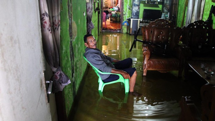 Seorang warga duduk di dalam rumahnya yang tergenang banjir rob di Kecamatan Dumai Barat, Dumai, Riau, Kamis (17/10/2024). Sejumlah kecamatan yang letaknya berdekatan dengan garis pantai di wilayah tersebut menjadi langganan banjir rob yang menyebabkan aktivitas warga terganggu dan rentan terhadap munculnya berbagai penyakit. ANTARA FOTO/Aswaddy Hamid/tom.