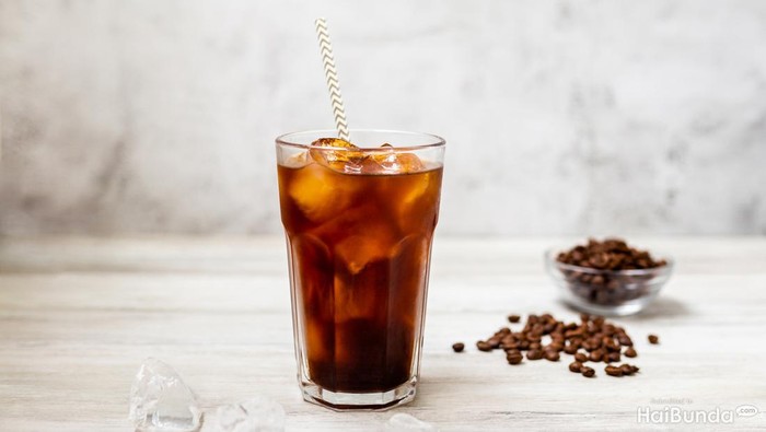 Ice coffee in a tall glass. Cold summer drink on a wooden background with copy space.