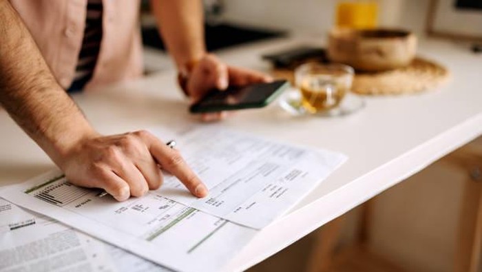 Unrecognisable man using calculator on the phone to calculate expenses