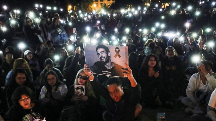 A woman holds a poster with an image of Liam Payne next to other One Direction fans as they gather to pay tribute to Liam Payne, at the Monument of the Revolution, in Mexico City, Mexico October 17, 2024. REUTERS/Henry Romero