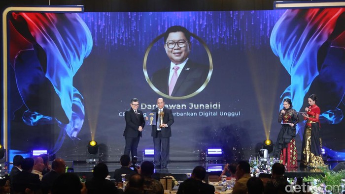 Pimpinan Redaksi detikcom, Alfito Deanova, memberikan penghargaan kepada Darmawan Junaidi sebagai CEO dengan Visi Perbankan Digital Unggul dalam detikcom Awards 2024. Event ini digelar di The Westin Jakarta, Kamis (17/10/2024).