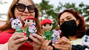 Para penggemar memegang boneka karakter milik anggota boy band K-pop BTS, J-Hope, sambil menunggu J-Hope.