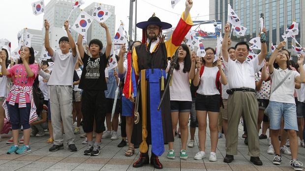 Ilustrasi warga Korea Selatan mengangkat bendera. (AP Photo/Lee Jin-man)