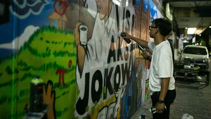 Menyambut kepulangan Presiden Joko Widodo ke kampung halamannya di Solo, sekelompok anak muda dari komunitas lokal menghiasi dinding pertokoan di Jalan Slamet Riyadi dengan mural. Karya seni ini menampilkan berbagai capaian 10 tahun pemerintahan Jokowi.