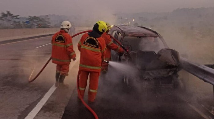 Petugas Damkar Salatiga memadamkan mobil yang terbakar di Tol Semarang, Sabtu (19/10/2024).