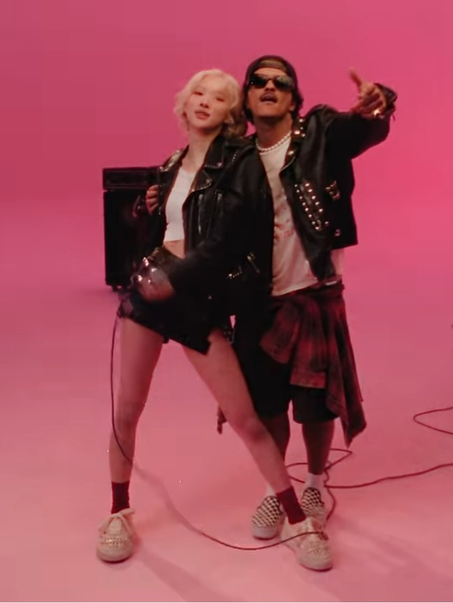 Bruno Mars tak kalah tampil atraktif. Musisi yang populer dengan lagu ’The Lazy Song’ ini juga tampil dengan jaket stud, kaus putih dan celana bermuda dengan kemeja flanel yang dililit di pinggang sebagai aksen. Foto: Screenshot YouTube/ROSE
