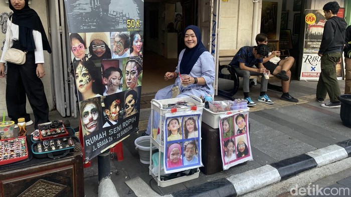 Rahma Widya sedang menjalani pekerjaannya dengan membuka jasa melukis wajah atau face painting di depan Rumah Seni Ropih, Jalan Braga, Kota Bandung.