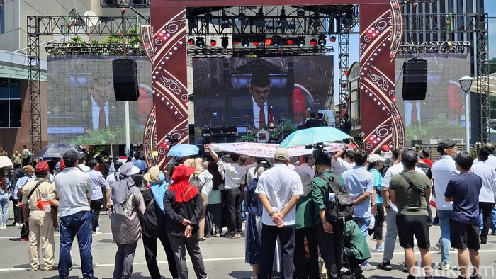 Warga antusias panas-panasan menyaksikan tayangan live streaming pelantikan Prabowo-Gibran melalui layar yang ada di panggung rakyat di Semanggi, Jakpus. (M Sholihin/detikcom)