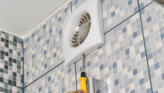the master removes the ventilation grill in the bathroom with a screwdriver